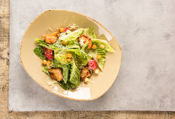 Caesar salad with chicken. Romano lettuce, chicken fillet, tomatoes, croutons, parmesan cheese and sauce in a plate on a light background. Restaurant. Background image, copy space. Flatlay, top view