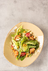 Caesar salad with chicken. Romano lettuce, chicken fillet, tomatoes, croutons, parmesan cheese and sauce in a plate on a light background. Restaurant. Background image, copy space. Flatlay, top view