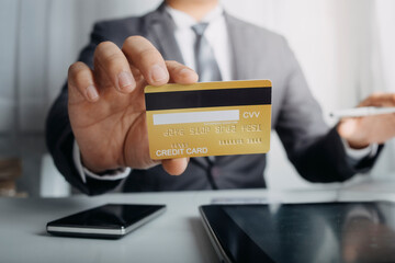 Business people use tablets and hold credit cards as an online shopping concept With a calculator and a book placed on the table
