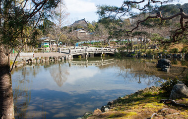 Fototapeta na wymiar A Japanese style bridge over water in Maruyama Park near Yasaka Shrine in Kyoto in Japan in spring