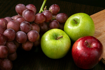 fruit still life with grapes and green and red apple on a black background