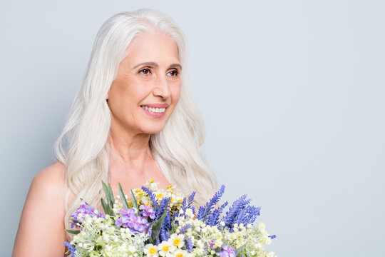 Photo of beautiful retired lady hold big bunch wild flowers look empty space surprise isolated grey color background