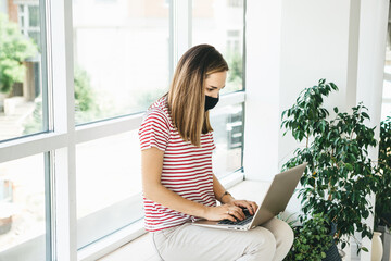 Girl with face mask and laptop.