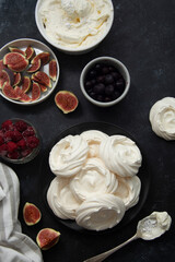 Cooking dessert. Abstract food background. Top view of mini Pavlova meringue cakes decorated with berries and figs.
