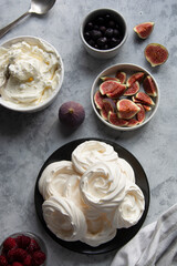 Cooking dessert. Abstract food background. Top view of mini Pavlova meringue cakes decorated with berries and figs.