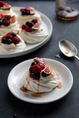 Mini Pavlova meringue cakes decorated with berries and figs.