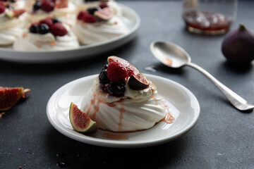 Mini Pavlova meringue cakes decorated with berries and figs.
