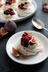 Mini Pavlova meringue cakes decorated with berries and figs.