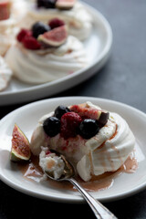 Mini Pavlova meringue cakes decorated with berries and figs.