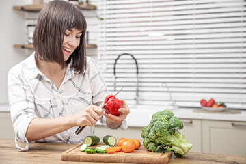 Young beautiful woman preparing fresh vegetable salad. Healthy food and diet concept.