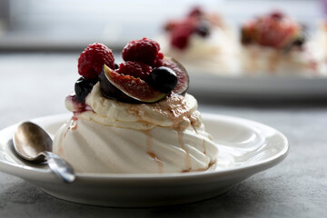 Mini Pavlova meringue cakes decorated with berries and figs.