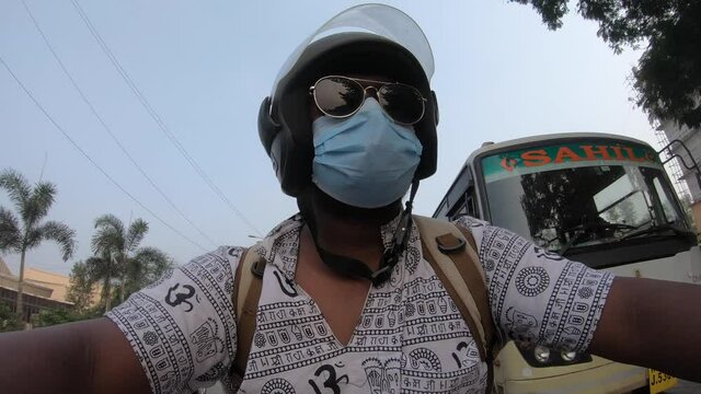 Boy man with hippy shirt om print riding a bike in traffic with a mask on face goggles and helmet shot