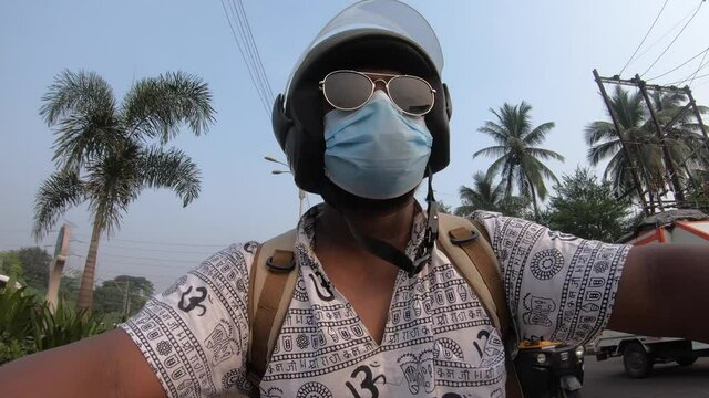 boy man with hippy shirt om print riding a bike in traffic with a mask on face goggles and helmet GoPro shot commercial