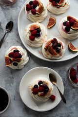 Mini Pavlova meringue cakes decorated with berries and figs.