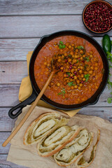 Middle Eastern chickpeas in cast iron pan on wooden table, bread, copy space
