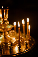 Photo with film grain: Wax candles in a wooden Orthodox church on a golden candlestick in a dark room