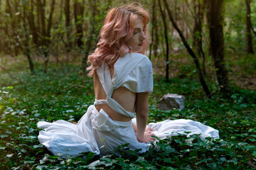 A woman in a white dress in the middle of the forest