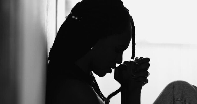 Silhouette meditative black woman praying during hard times