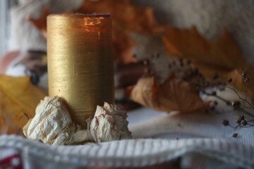 Tall golden candle with dried flowers at the base and autumn background