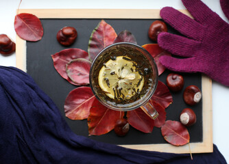 Composition with cup of tea, glove, scarf, chestnuts and leaves.