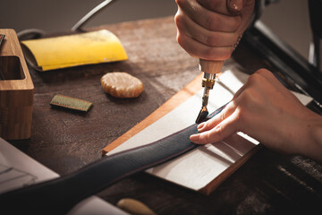 Leather handbag craftsman at work in a vintage workshop. Small business concept