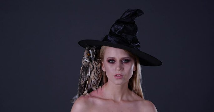 Beautiful witch with her owl familiar on grey background, closeup