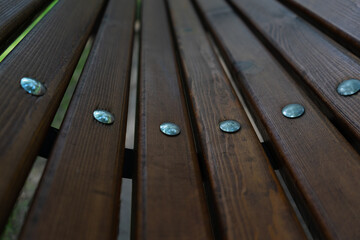 Fototapeta premium elements of the bench. Wooden slats with metal nails with round cap. Selective focus. bench in the city Park
