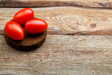 red tomatoes on a round board on a wooden table.