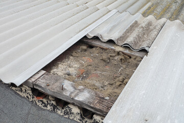 Old damaged asbestos-cement roof with wet insulation