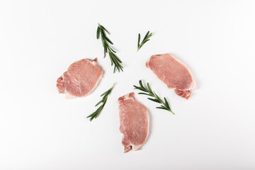 Raw fresh pork sliced meat with rosemary on white background. Flat lay, top view
