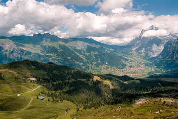 High angle view on alpine village Grindelwald in the Bernese Oberland, surrounded by high snow capped mountains. Seen from mountain Männlichen in summer