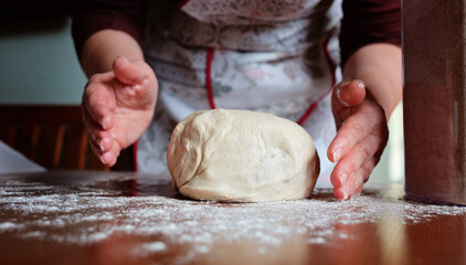 Senior woman hands knead dough on a table in her home kitchen