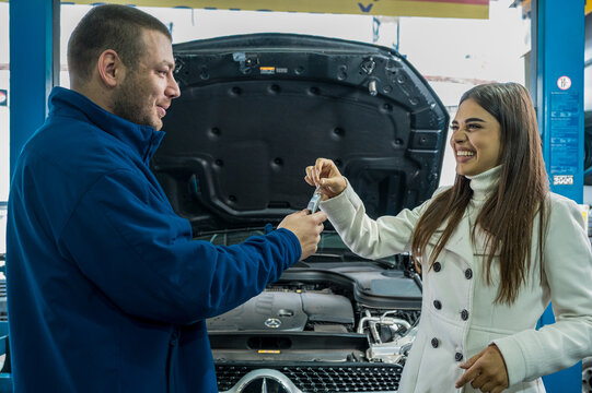 A female client giving keys to car mechanic in the garage
