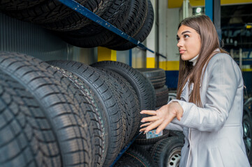 Obraz na płótnie Canvas Confused female choosing tires in the garage