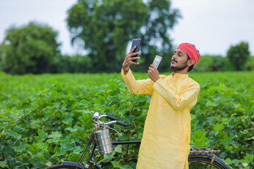 Indian farmer take selfie with money at cotton field and showing happy expression