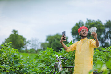 Indian farmer take selfie with money at cotton field and showing happy expression