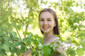 portrait of a cute girl without makeup on a green tree background. the concept of natural beauty. fresh young face