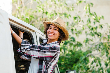 Young farmer woman in a van looking out at crop field