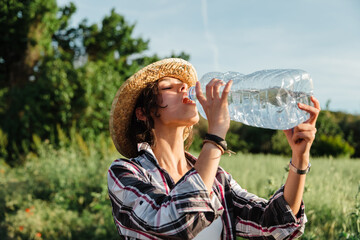 Farmer woman drinking water from plastic bottle during harvesting paddy at rice field.
