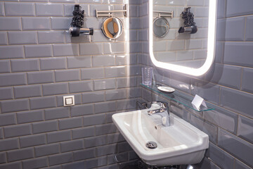 Sink in the bathroom. Fragment of bathroom interior. Mirror above the ceramic sink. Pastel purple...