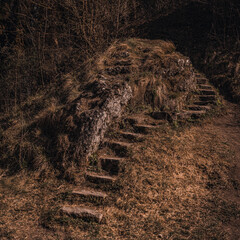 Old abandoned dilapidated stone steps in nature overgrown with moss near the mountain.