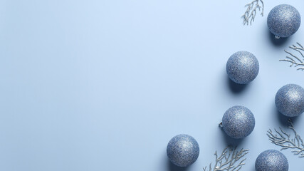 Blue Christmas background with balls decoration and silver fir branches. Minimalist style. Flat lay, top view. Xmas greeting card template, banner mockup.