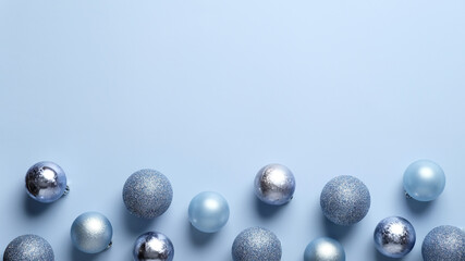 Christmas frame border made of blue and silver balls decoration on pastel blue background. Flat lay, top view. Christmas greeting card template, banner mockup.
