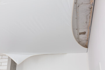 repairmen install stretch ceiling made of pvc vinyl film using a gas heat gun