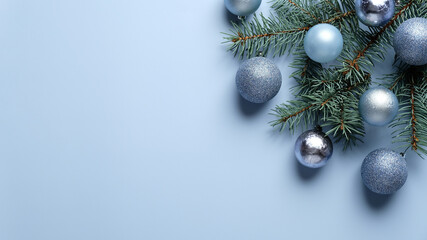 Elegant Christmas composition with blue and silver balls decoration and pine tree branch on pastel blue background. Flat lay, top view.