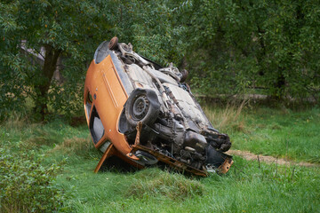 Schrottauto orange auf Wiese in Polen