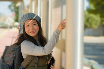 outdoors lifestyle portrait of young beautiful and happy Asian Japanese woman waiting the train on station platform bench checking travel and itinerary schedule