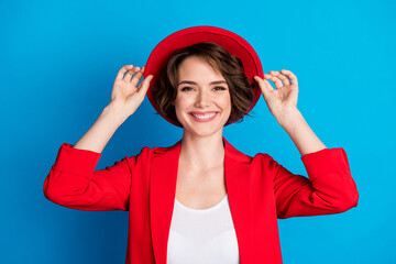 Close-up portrait of attractive cheerful lady wearing touching sunhat isolated over bright blue color background