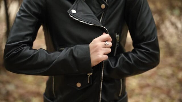 A young woman takes refuge in a black leather jacket. Outer autumn clothes on a woman
