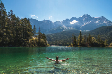 Man swimming in a beautiful mountain lake in the middle of the nature in the Bavarian Alps,...